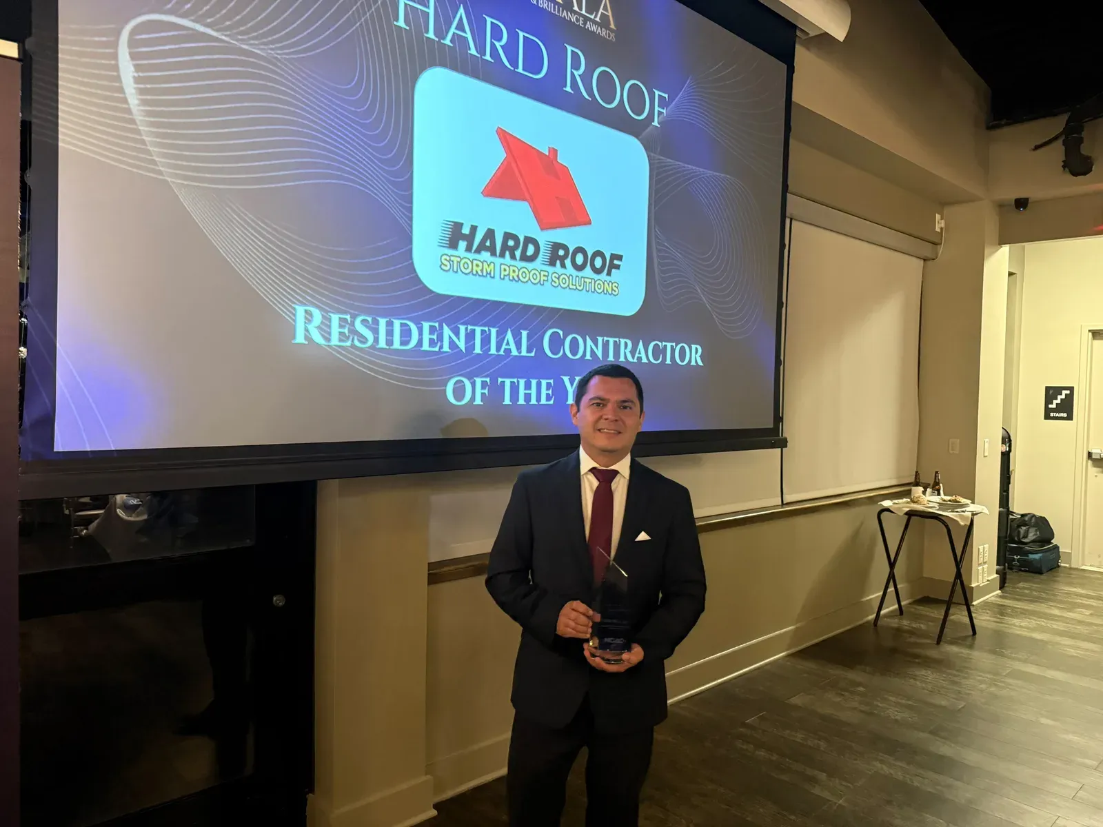 Christian Romero Arias of Hard Roof holding the HCAC Residential Contractor of the Year award at the 2026 Brilliance Awards gala